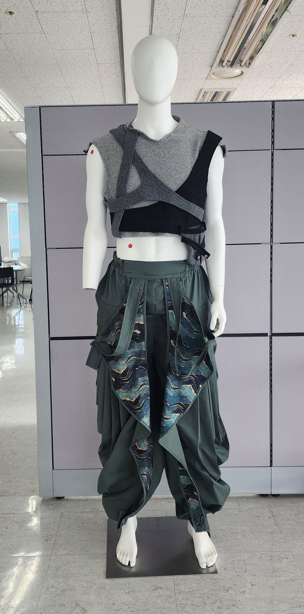 Mannequin wearing a grey strap top and green draped trousers