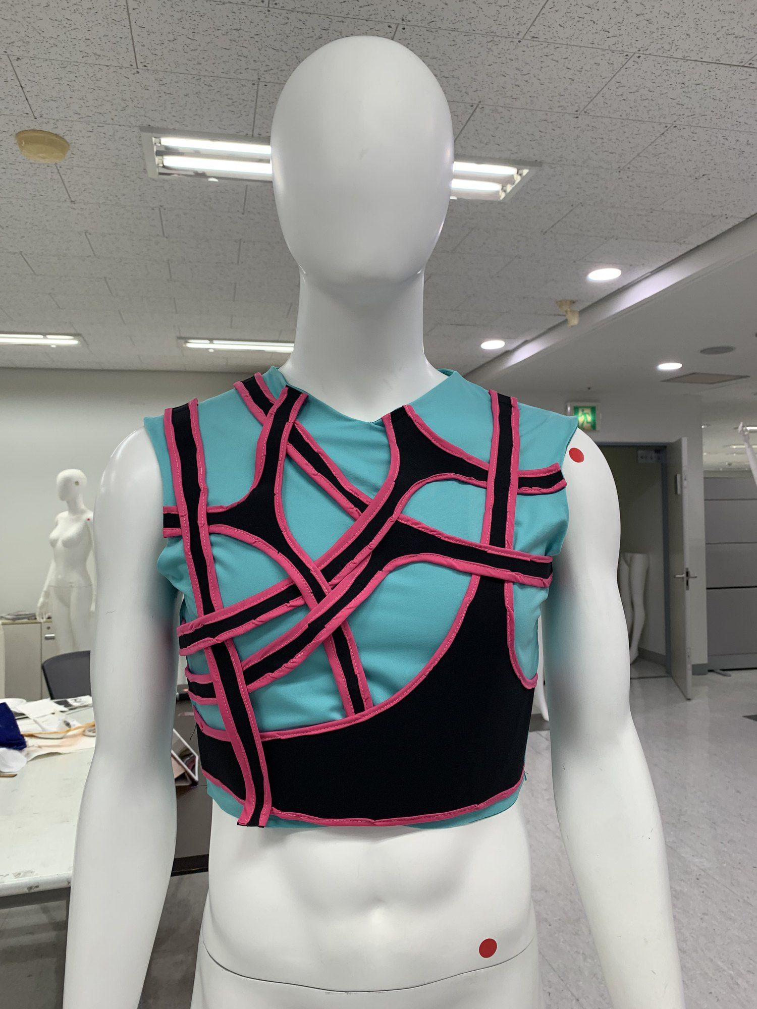 Cyan bodysuit with pink and black straps on a mannequin