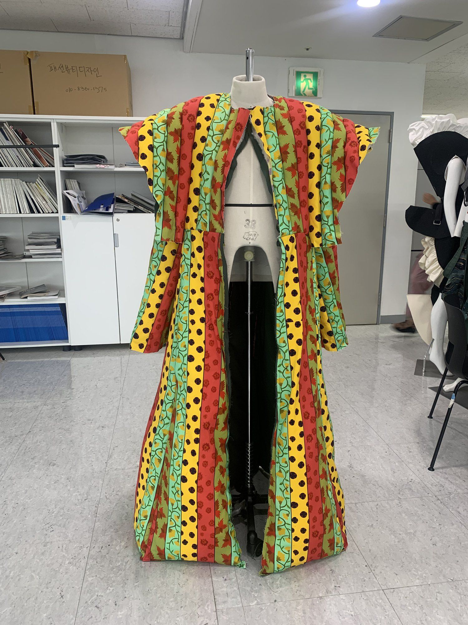 Long printed coat in yellow, red and green on a mannequin