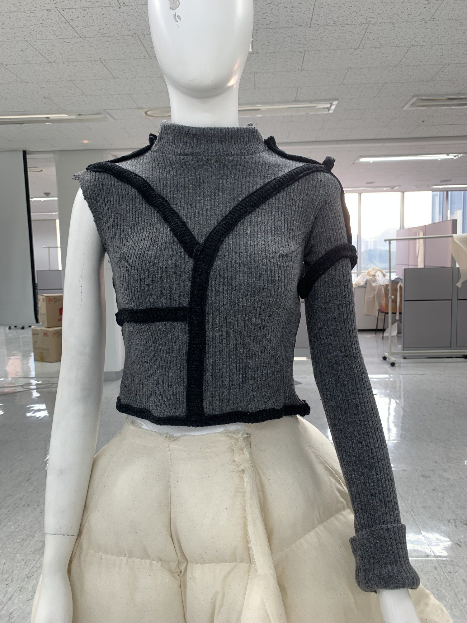 Grey knit top with black binding on a mannequin
