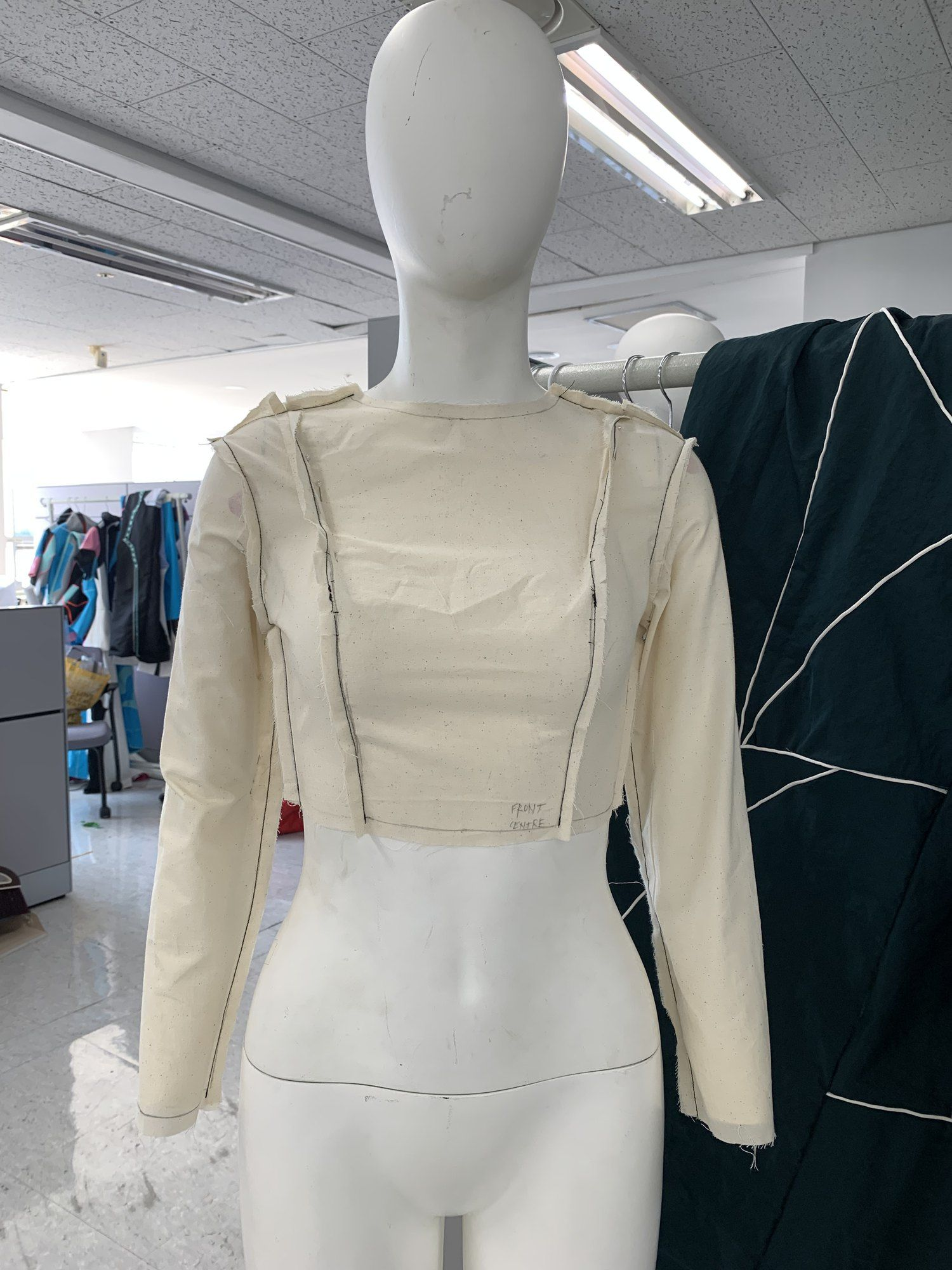 Calico toile of a cropped jacket, front, with coloured pins